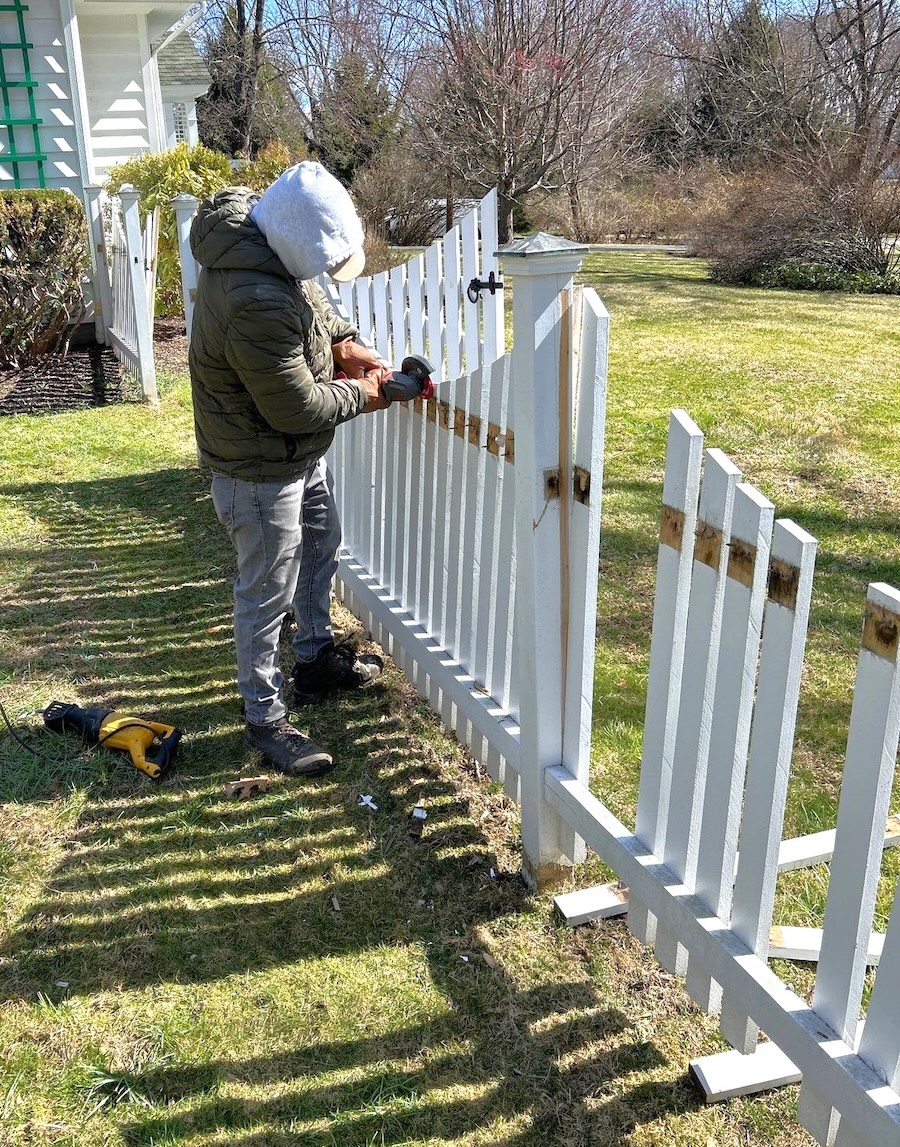carpenter fixing a white fence
